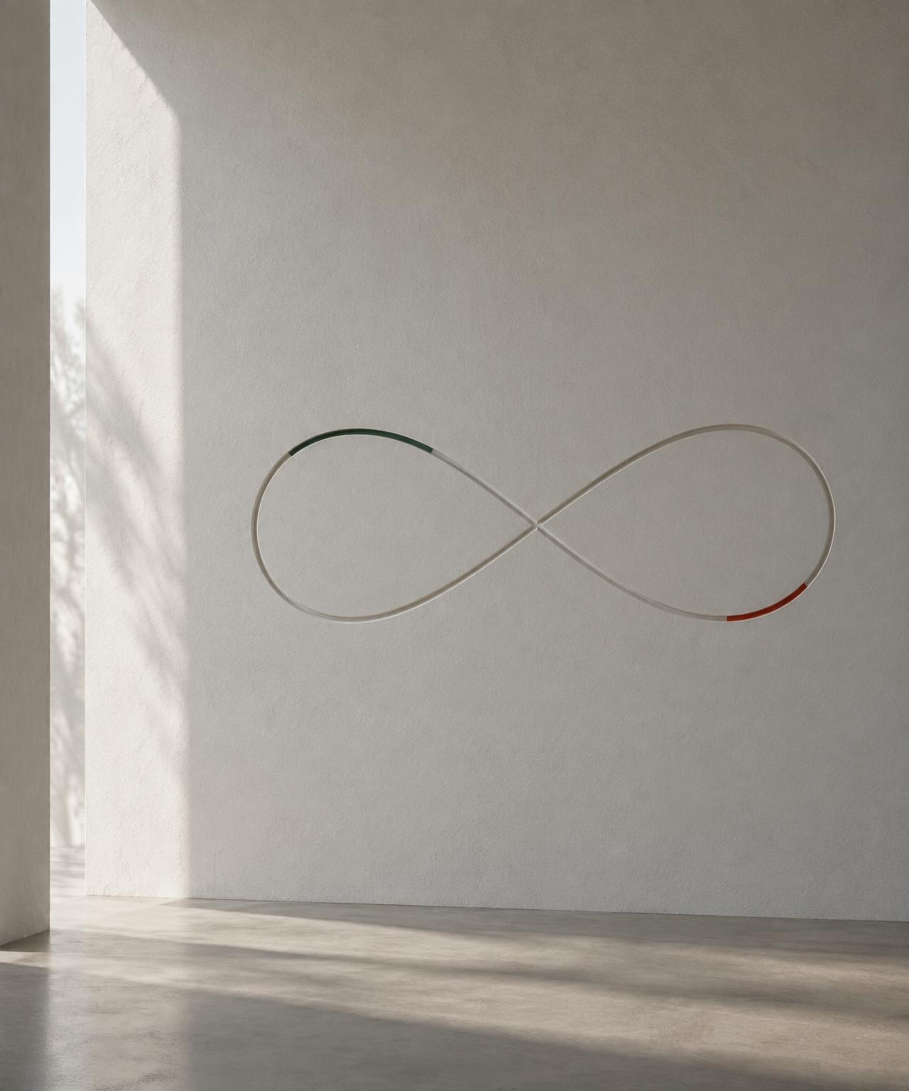 A thin infinity symbol traced across a quiet white plaster wall, with a green segment and a red segment